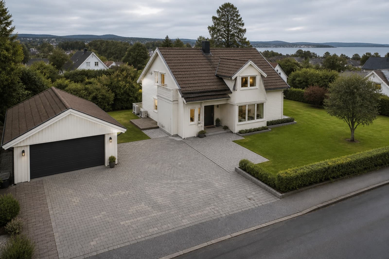 Boligtomt sett ovenfra med hus, garasje, innkjørsel og hage